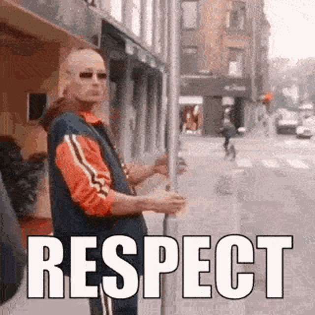 a man is standing on a sidewalk in front of a building holding a sign that says `` respect '' .