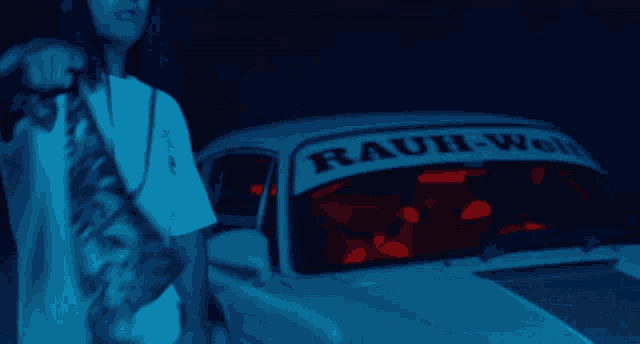 a man stands in front of a car with a rauh-woll banner on the windshield