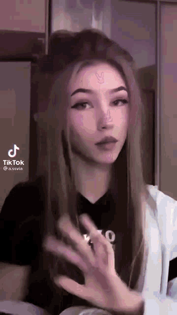 a girl with a bunny tattoo on her forehead is making a funny face .