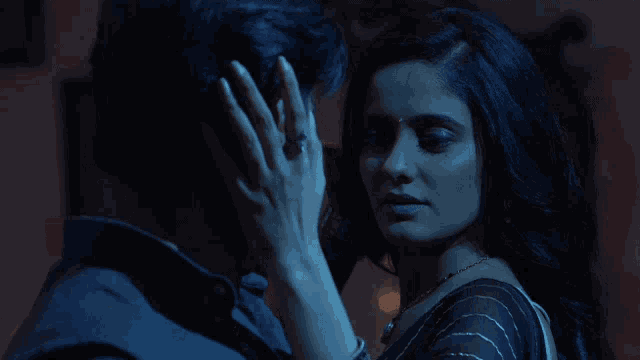 a woman is touching a man 's face with her hand