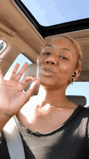 a woman sitting in a car making a funny face