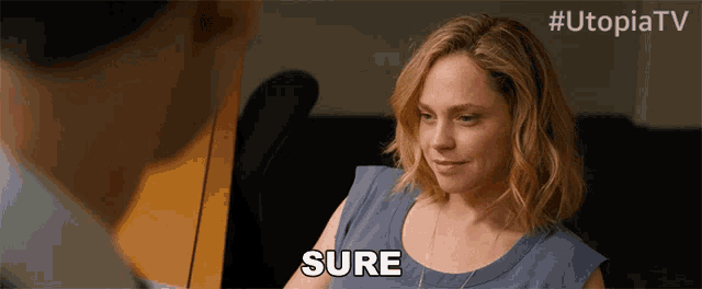 a woman in a blue shirt says sure in front of a man in a suit
