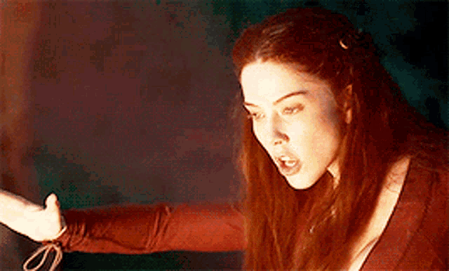 a woman with red hair is standing in front of a fire .