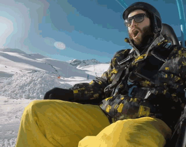 a man wearing sunglasses and a helmet is riding a ski lift in the snow