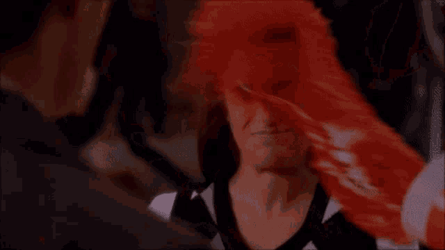 a woman is covered in blood and screaming while a man looks on .