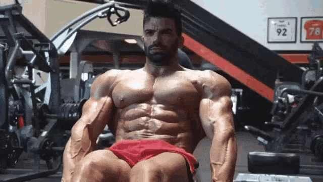 a man is sitting on a machine in a gym .
