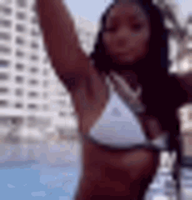 a woman in a white bikini is standing in front of a pool .