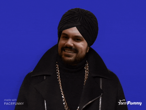 a man wearing a turban and gold chains is giving a thumbs up