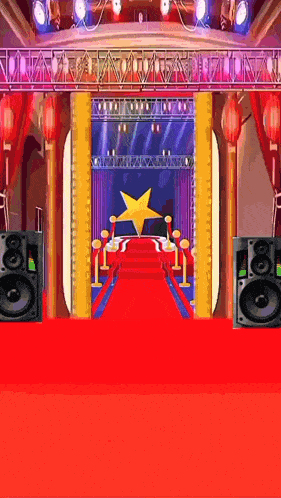 a red carpet leading to a stage with speakers and a star