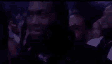 a man is sitting in a crowd of people at a concert and looking at the camera .