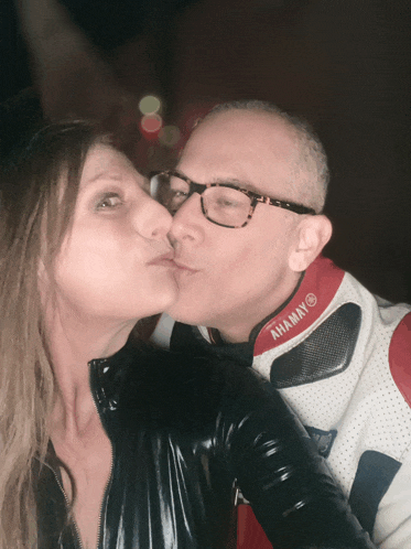 a man kissing a woman wearing a jacket that says ahamay