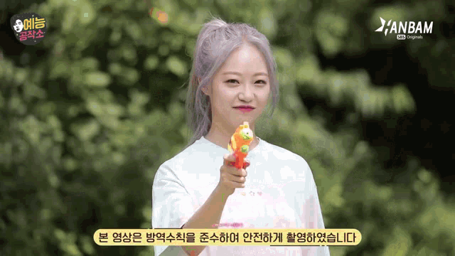 a girl in a white shirt is holding a water gun in front of an anbam logo