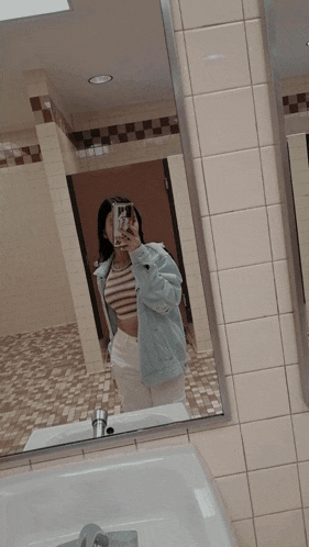 a woman taking a picture of herself in a mirror