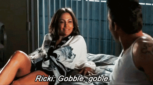 a woman laying on a bed talking to a man who says ricki gobble gobble