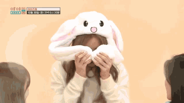a girl wearing a white bunny hat with korean writing on the bottom