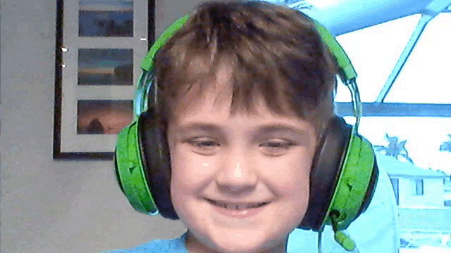 a young boy wearing a pair of green headphones with a microphone