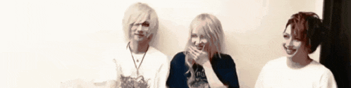 three people are standing next to each other and one of them is covering her mouth with her hands