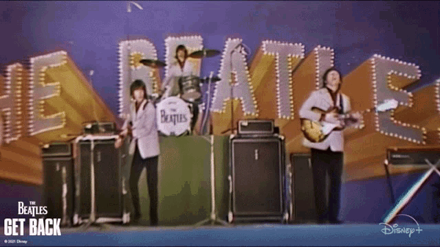 the beatles are playing on stage in front of a sign that says " get back "