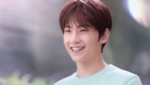 a young man in a green shirt is smiling and looking at the camera .