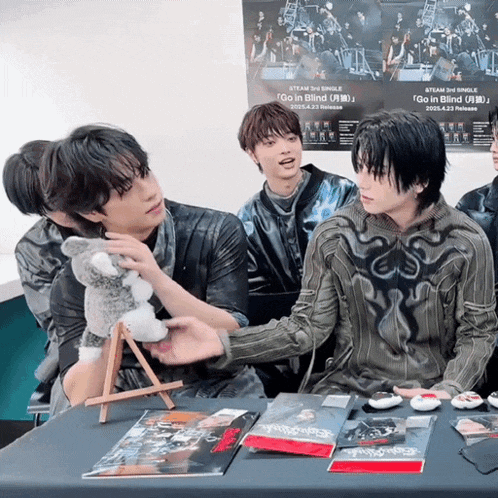 a group of young men are sitting around a table with a poster that says go in blind on it