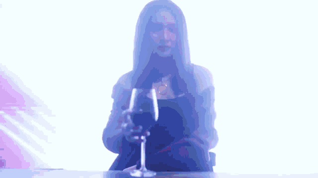 a woman is sitting at a table holding a glass of wine in her hand .