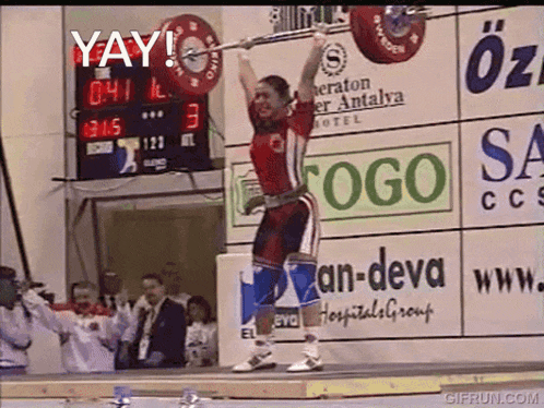 a man lifts a barbell in front of a sign that says " yay "