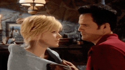 a man and a woman are looking at each other in a living room