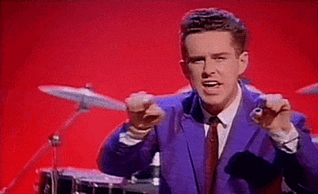 a man in a blue suit and tie is singing into a microphone