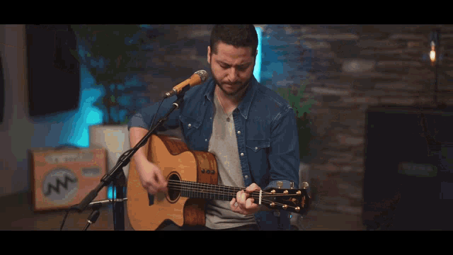 a man is singing into a microphone while playing a guitar