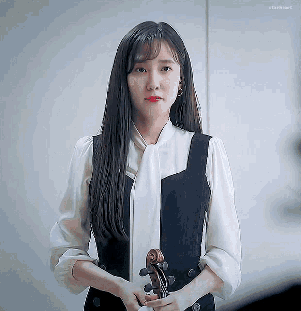 a woman in a black and white dress is holding a violin .