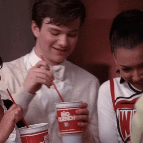 a man in a bow tie drinks from a big gulp cup with a straw