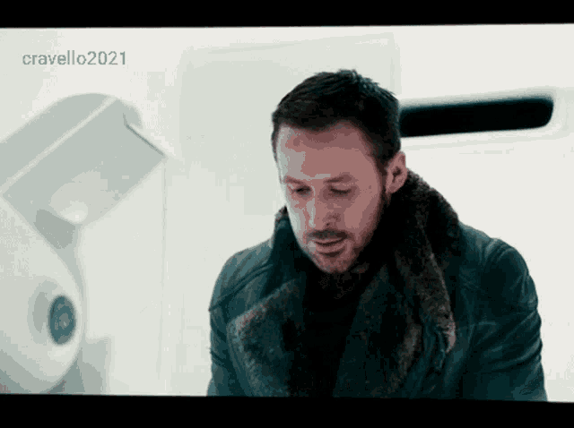 a man in a fur coat is standing in front of a white wall with the year 2021 on the bottom