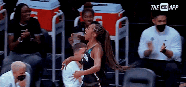 a woman in a black tank top is hugging a man in a white shirt .