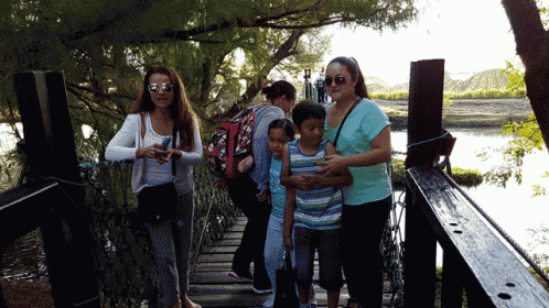 a group of people are standing on a bridge over a river