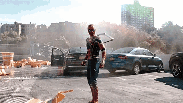 a man in a spiderman costume is standing in a parking lot with cars