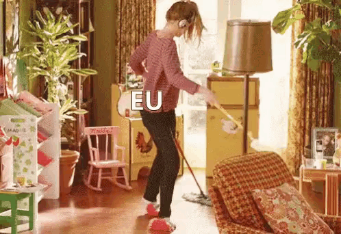 a woman is mopping the floor in a living room while wearing headphones and the word eu is on her back .