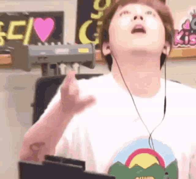 a man wearing headphones and a t-shirt with a rainbow on it is standing in front of a keyboard .