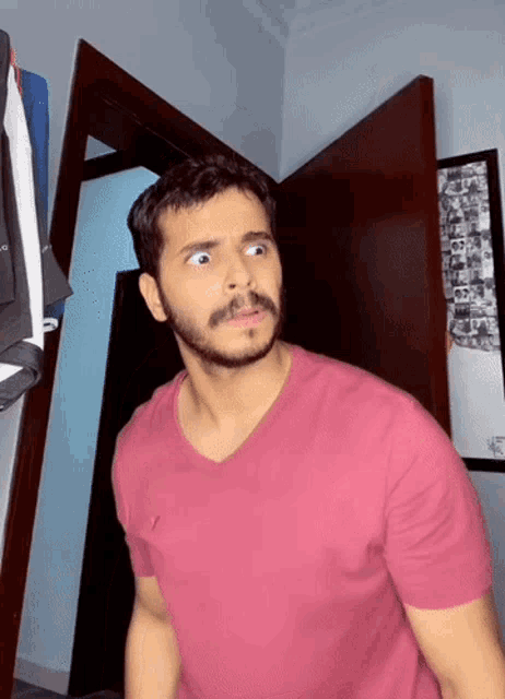 a man in a pink shirt is standing in a room