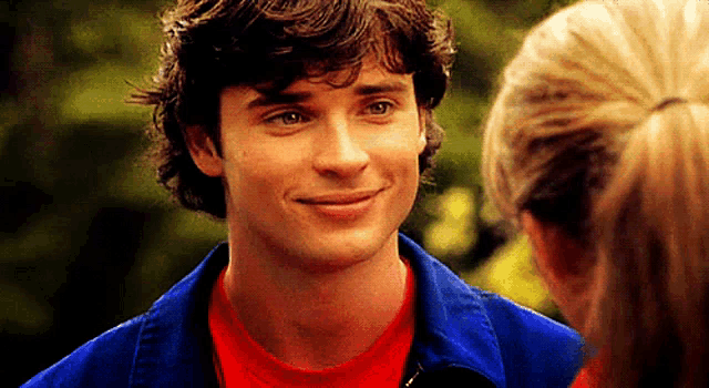 a man wearing a blue jacket and a red shirt smiles at a woman