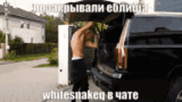 a shirtless man is standing in the back of a black suv .