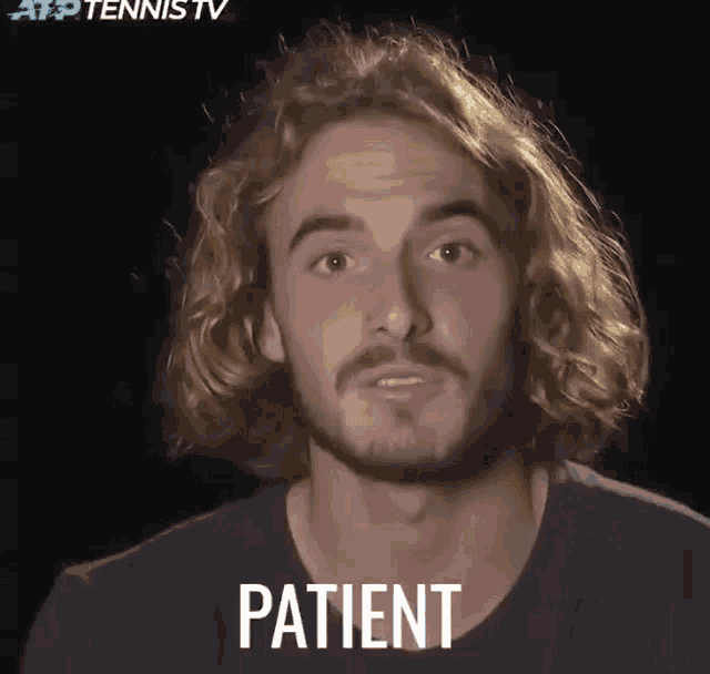 a man with long hair and a beard says patient in front of a black background