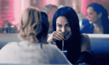 a woman with blue hair is sitting at a table with another woman .