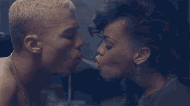a man and a woman are kissing in a dark room with smoke coming out of their mouths .