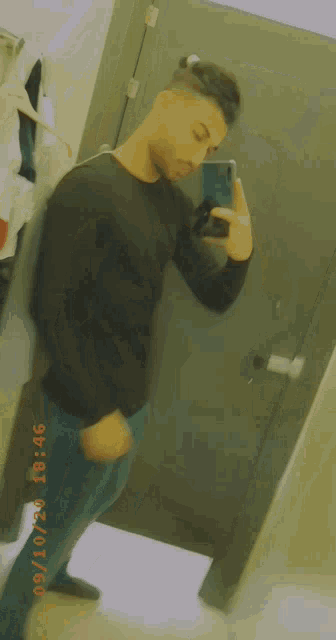 a man in a black shirt is taking a picture of himself in a mirror