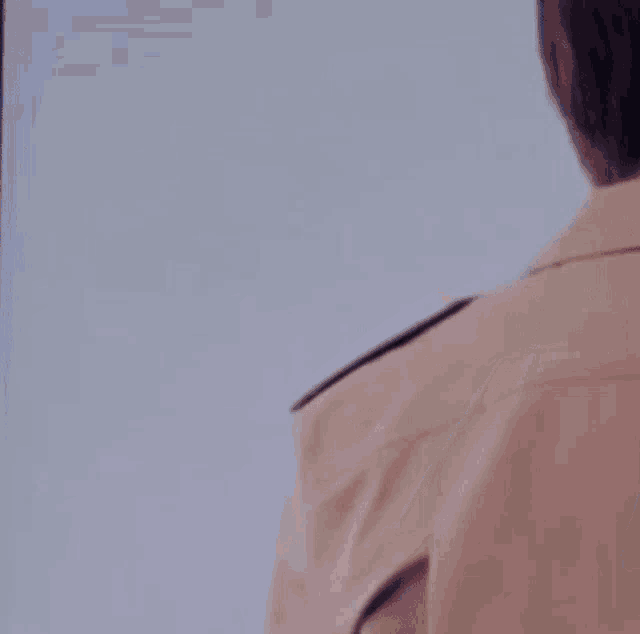 a young man wearing a blue sweater is standing in front of a wall .