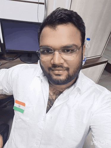 a man wearing glasses and a white shirt with an indian flag on his pocket
