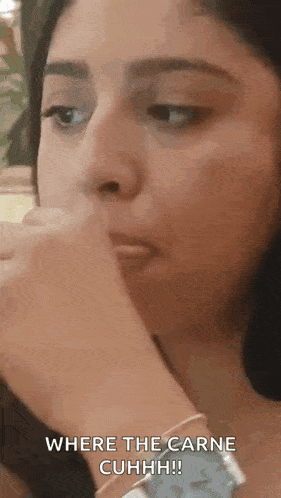 a close up of a woman covering her mouth with her hand .