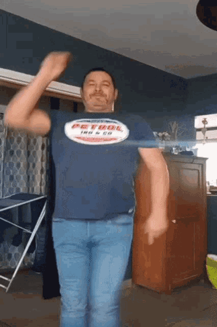 a man in a petrol shirt is dancing in a room