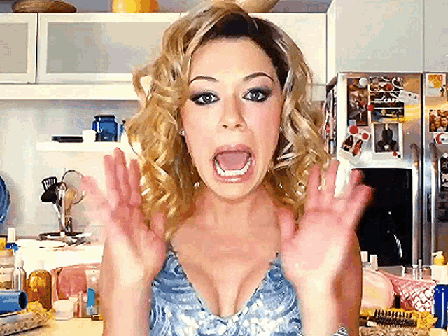 a woman is making a surprised face in front of a refrigerator