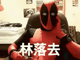 a man in a deadpool costume sits in a chair